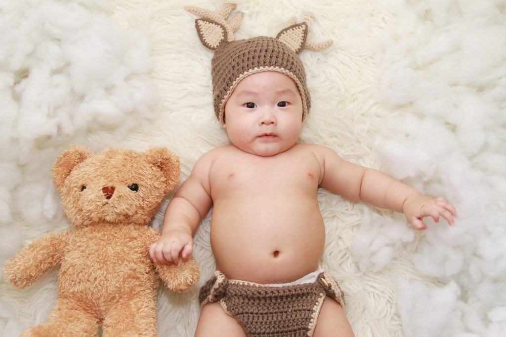 Adorable asian boy with knitted fox ear beanie holding teddy bear