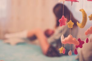 Mom breastfeeding baby on bed near mobile