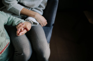 Woman holding child's hand sitting on chair