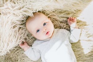 Beautiful baby lying on fur blanket with eyes open