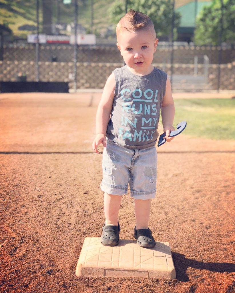 young boy on baseball diamond holding number 2