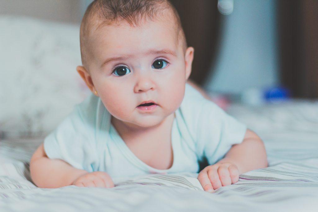 Adorable baby on bed in blue onesie