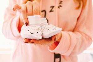 Mom holding newborn baby lamb shoes wearing sleepy pajamas