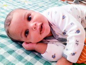 Adorable baby boy lying on plaid blanket