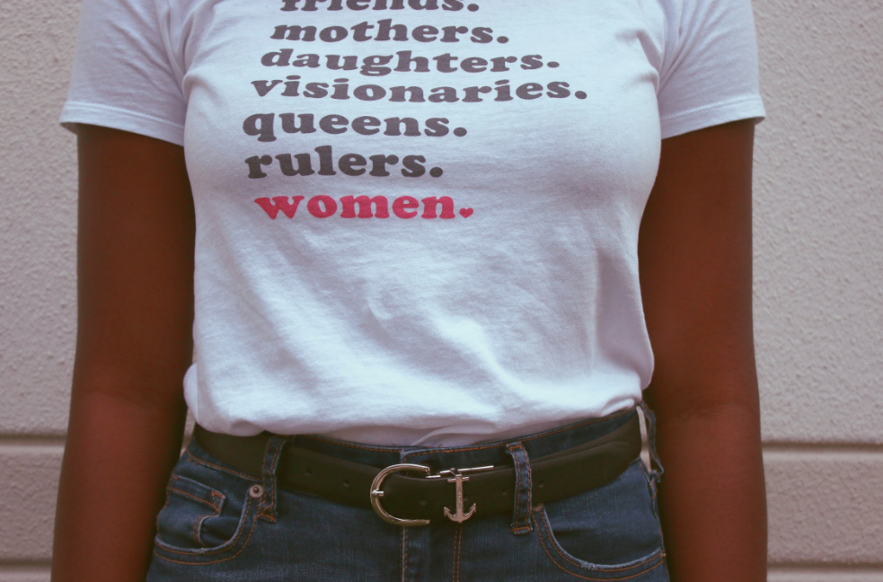 Woman wearing shirt reading friends, mothers, daughters, visionaries, queens, rulers, women