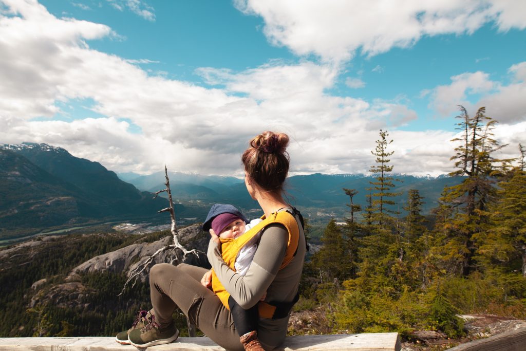 Hiking mom wearing baby over beautiful vista