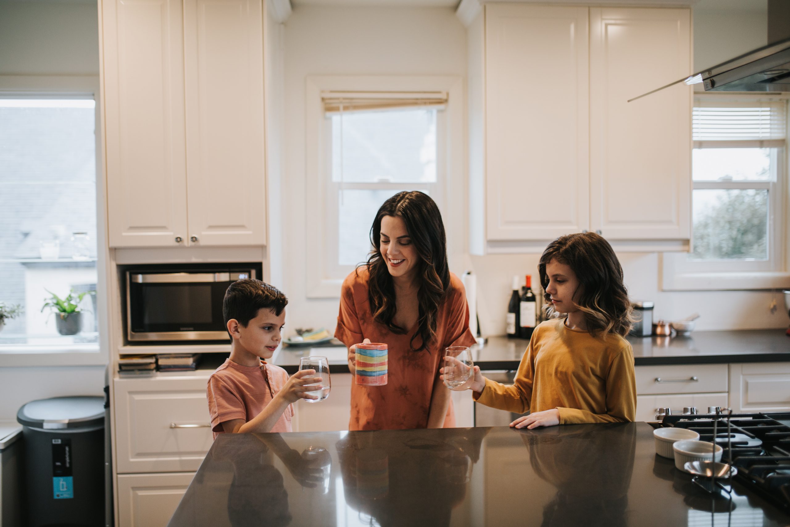 Natalie Willes and her two children in a kitchen doing cheers with mugs