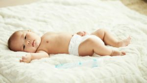 cute asian baby laying on white soft bedspread